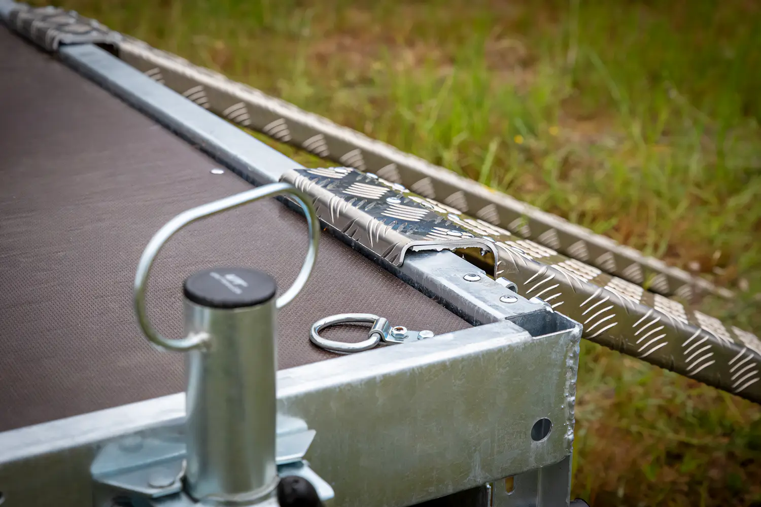 Close-up van de vloerogen (sjorogen voor het vastzetten van lading) en een metalen constructie-element op het laadvlak van de aanhangwagen.